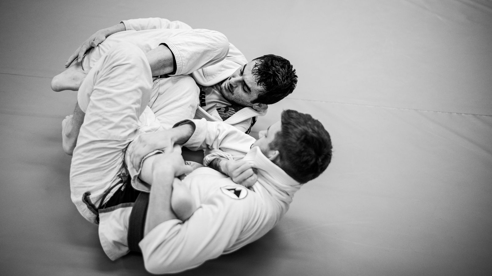 Dos practicantes de jiu-jitsu brasileño disputan una posición en el suelo.
